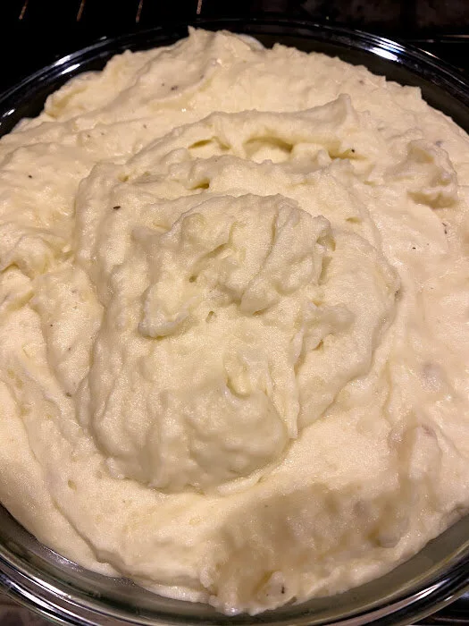 Creamy mashed potatoes in a glass bowl, showcasing a fluffy texture and smooth consistency, perfect as a side dish for various meals.