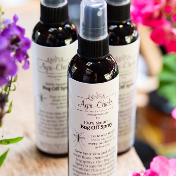 Bottles of Agri-Chicks 100% Natural Bug Off Spray displayed among colorful flowers, highlighting the product's organic ingredients and eco-friendly pest repellent benefits.